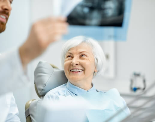 Older dental patient smiling at dentist