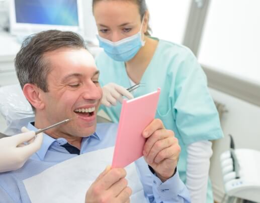 Man looking at his smile after dental bridge restoration