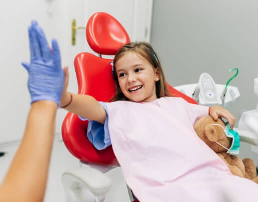 Child in dental chair giving dentist a high five