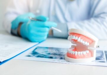 Dentist pointing to model smile with denture