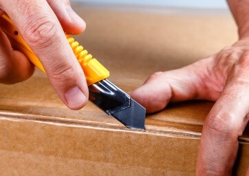 Person using a tool to open a package