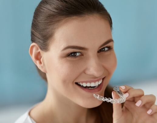 Smiling woman placing Invisalign clear braces