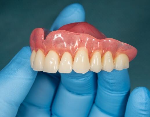 Hand holding a full denture