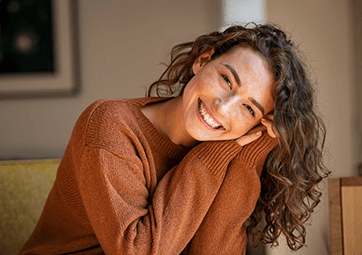 a woman smiling after paying for the cost of veneers